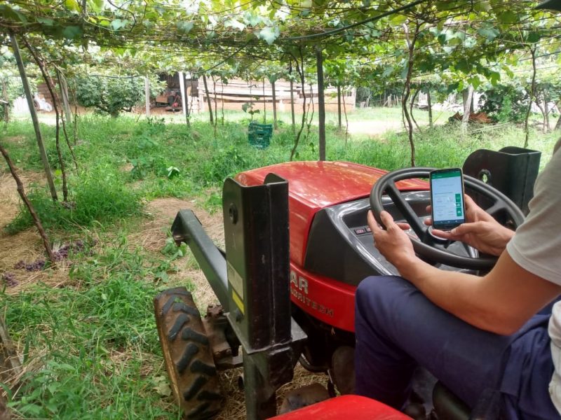 produtor com trator e celular